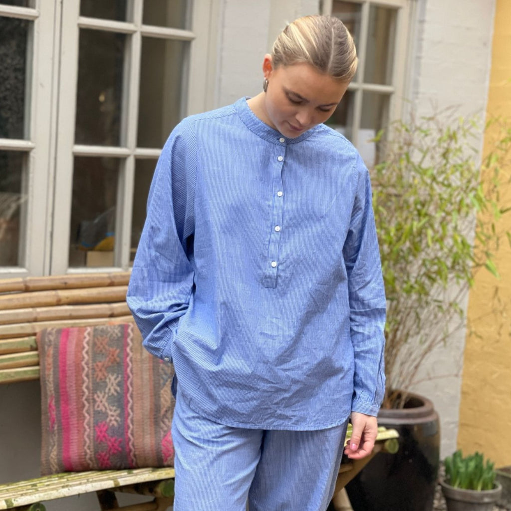 Den langærmet skjorte 'Madrid' i blå striber, fra danske Frau er den perfekte hverdagsskjorte. Skjorten har stolpelukning, og er lavet i en let bomuldspoplin, som gør skjorten åndbar og behagelig at have på. Modellen er one size og er lavet i 100% økologisk bomuld. 