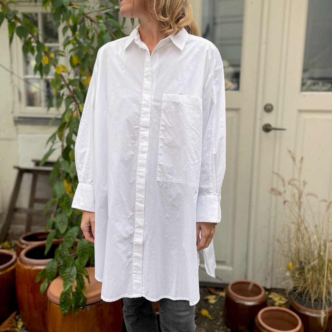 Den lange hvide bomuldsskjorte i er en perfekt hverdagsskjorte fra Frau. Skjorten er lidt længere bagpå og runder fint foran. Skjorten er gennemknappet, og er lavet i økologisk bomuldspoplin, som gør den åndbar og behagelig at have på. Størrelsen er one size